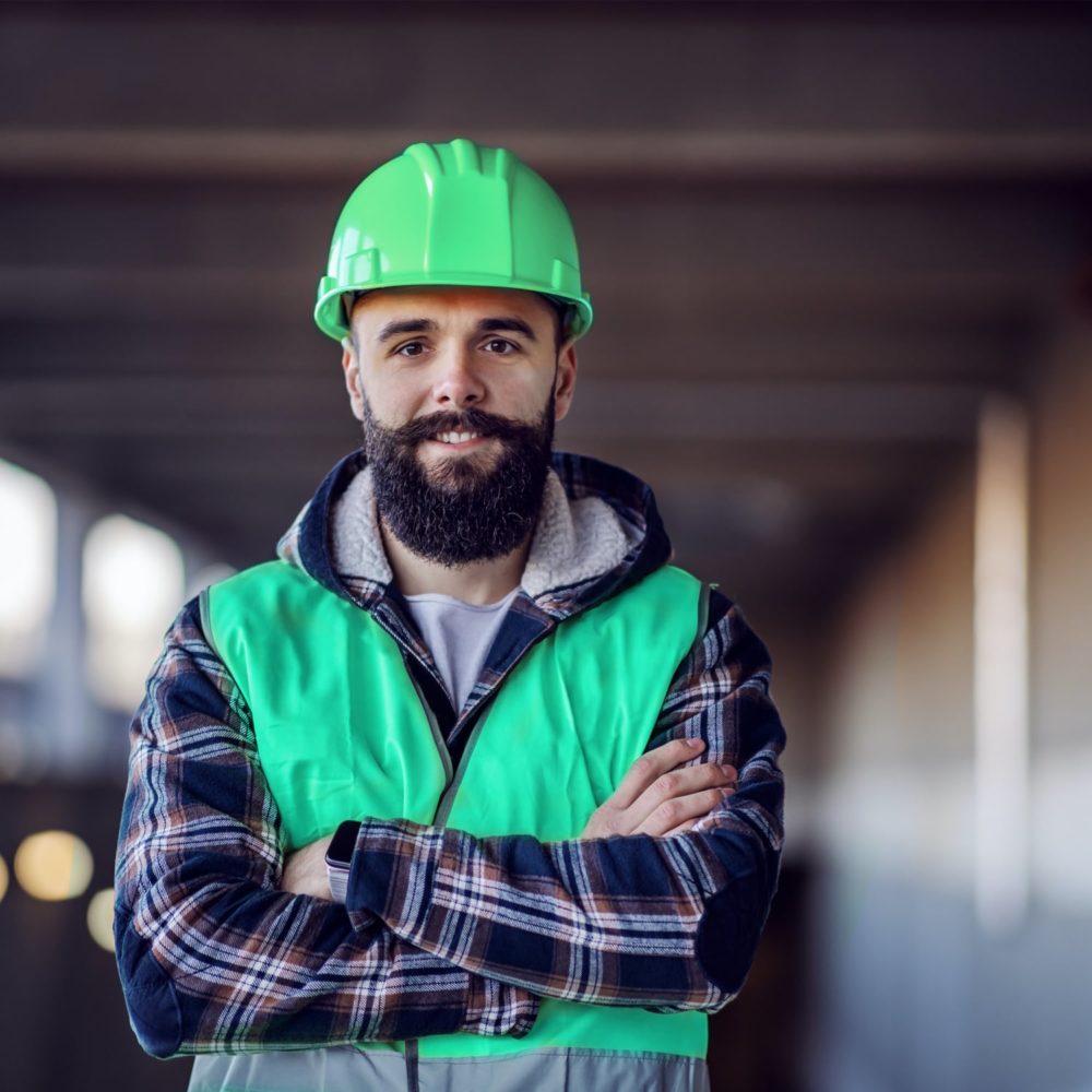 smiling male construction worker with green hard hat and reflective vest